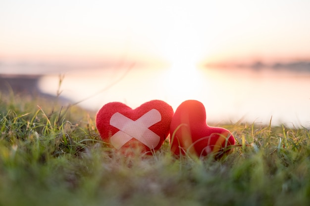 Corazón con yeso y corazón rojo en el fondo, cae el sol.