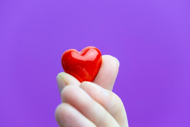 Un corazoncito de cristal rojo en los dedos