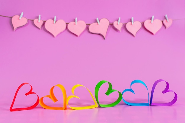 Corazones de amor con los colores de LGBT sobre fondo rosa