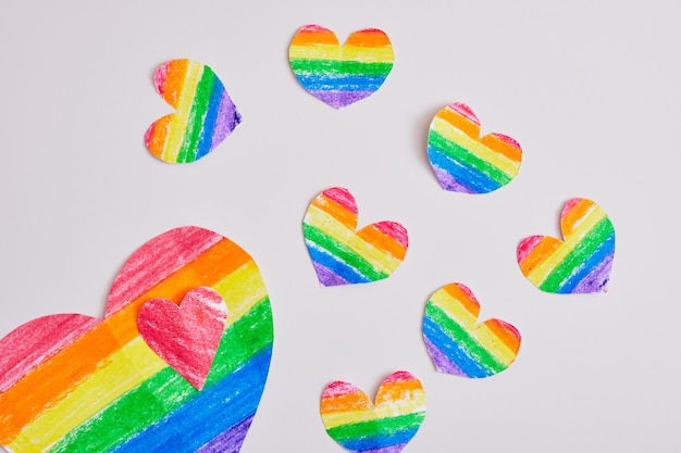 Corazones de arco iris caseros sobre un fondo gris, corazones dibujados y cortados en los colores de la bandera de la comunidad del orgullo lgbt