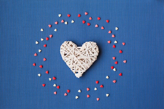 Foto corazones blancos sobre un azul están rodeados de caramelos de colores.