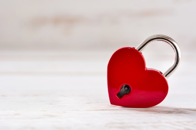 Corazones de candado rojo con llave sobre fondo blanco de madera