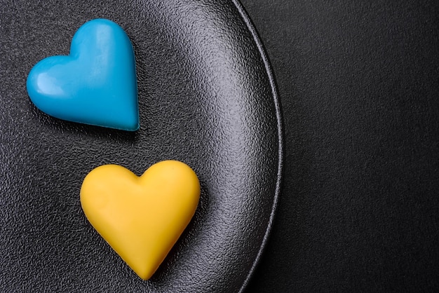 Corazones de chocolate con los colores de la bandera ucraniana en un plato de cerámica negra