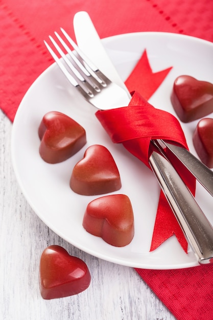 Corazones de chocolate y cubiertos en placa para San Valentín