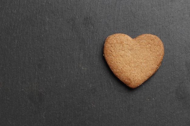 Corazones de galletas caseras deliciosas sobre un fondo oscuro. Vista superior. Lugar para el texto.