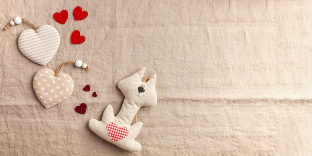 Corazones y gato de juguete sobre fondo beige textil banner del día de San Valentín