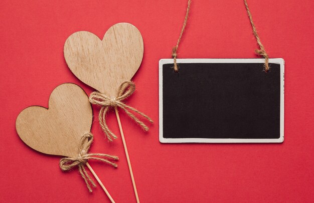 Foto corazones de madera y una pizarra colgada en una pared roja