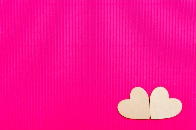 Corazones de madera sobre el fondo ondulado rosa.