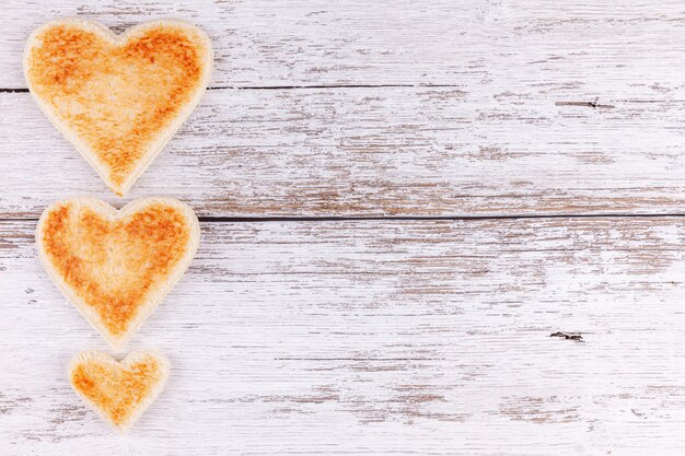 Corazones de pan tostado en la mesa de madera, concepto de desayuno en familia feliz