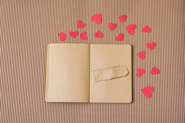 Corazones de papel alrededor de un cuaderno con papel rasgado