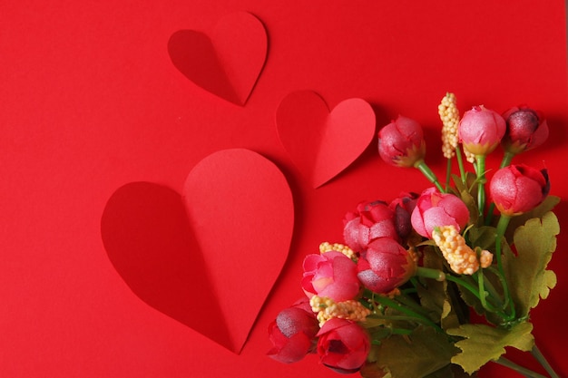 Foto corazones de papel con flores sobre fondo rojo.