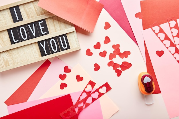 Foto corazones de papel de fondo del día de san valentín cortador de papel de papel de colores y texto de ingenio de tablero de letras