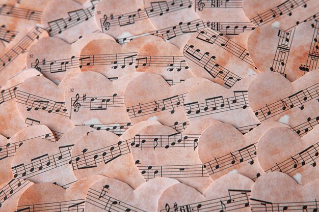 Foto corazones de papel con fondo de notas musicales.