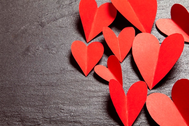 Corazones de papel hechos a mano rojos sobre un fondo de pizarra