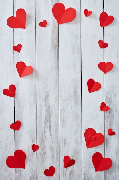 Corazones de papel rojo en mesa de madera blanca