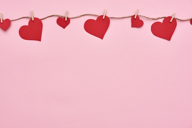 Corazones de papel rojo de San Valentín colgando en el tendedero