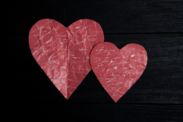 Foto corazones de papel rojo sobre superficie negra