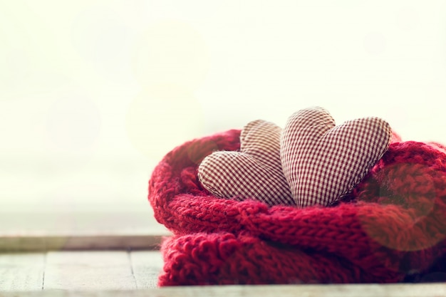 Corazones de peluche encima de una bufanda roja