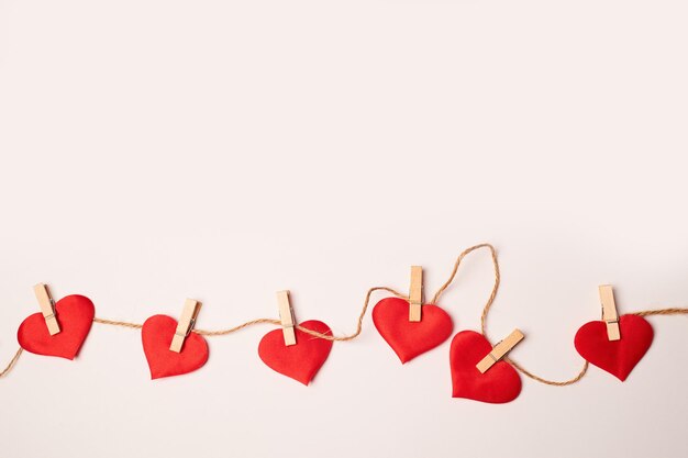 Corazones en pequeñas pinzas de madera sobre un fondo blanco. Felicitaciones por el día de san valentín.