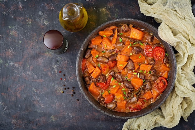 Corazones de pollo con calabaza y tomates en salsa de tomate. Endecha plana. Vista superior