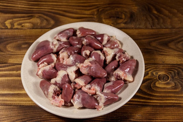 Corazones de pollo crudo en mesa de madera