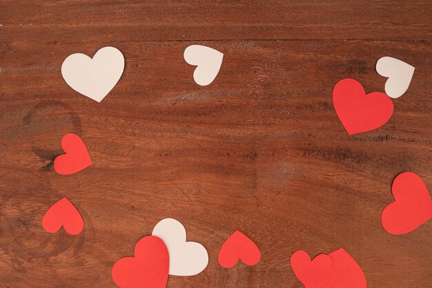 Corazones rojos y blancos de diferentes tamaños sobre fondo rústico de madera para el Día de San Valentín