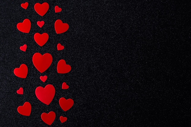 Corazones rojos brillantes para los amantes sobre un fondo negro Feliz Día de San Valentín