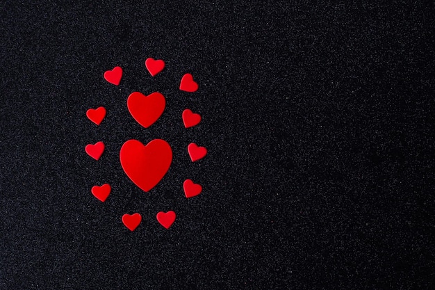 Corazones rojos brillantes para los amantes sobre un fondo negro Feliz Día de San Valentín