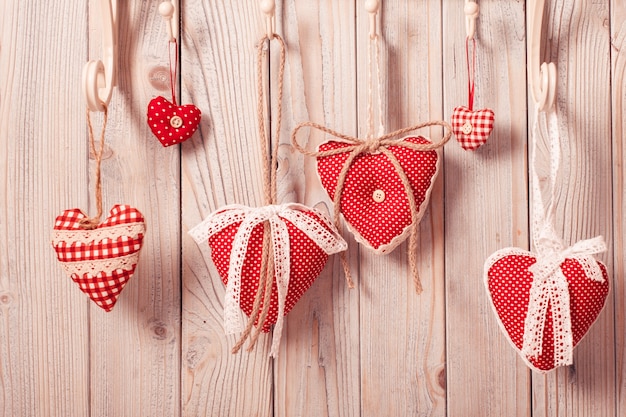 Corazones rojos colgando de los ganchos. Saludos de Navidad o San Valentín