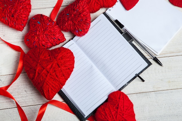 Corazones rojos con cuaderno, cinta roja y papeles