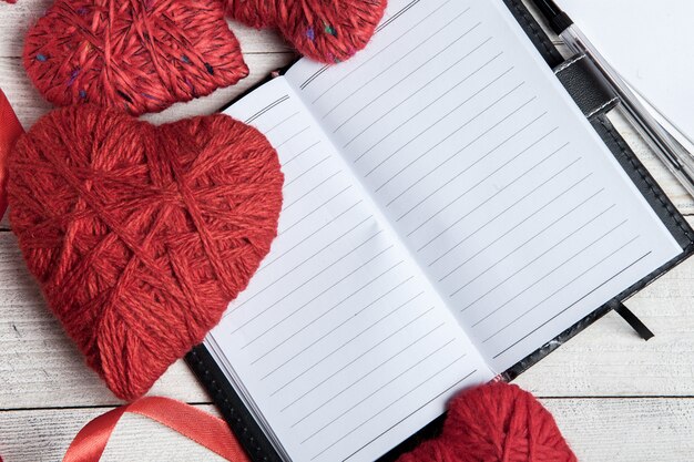 Corazones rojos con cuaderno, cinta roja y papeles