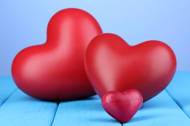 Corazones rojos decorativos en la mesa de madera azul sobre fondo azul.