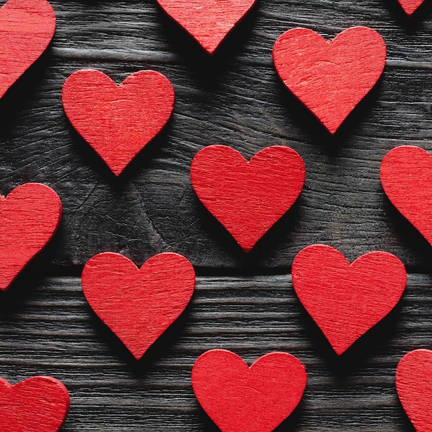 Corazones rojos de madera sobre fondo negro de madera