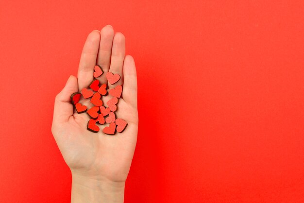 Corazones rojos en la mano de la mujer sobre un fondo rojo Espacio de copia