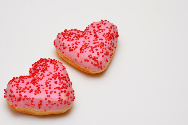 Corazones de rosquillas rosas en un primer plano de fondo blanco