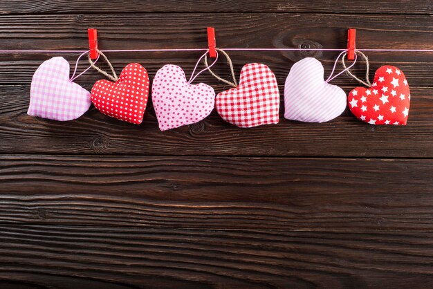 Corazones de San Valentín colgados de una cuerda sobre fondo de madera oscura.