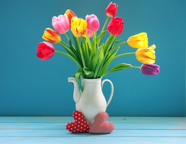 Corazones de tela y hermosos tulipanes de colores en florero