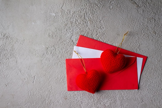 Foto corazones de terciopelo rojo yacen en sobres, sobre un fondo gris