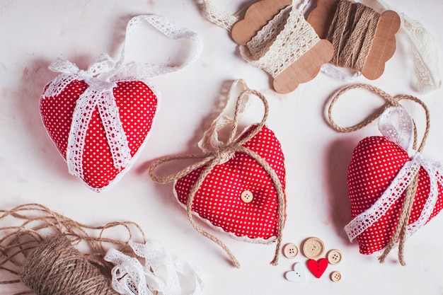 Corazones textiles de lunares rojos adornan la mesa. Proceso de costura y diseño