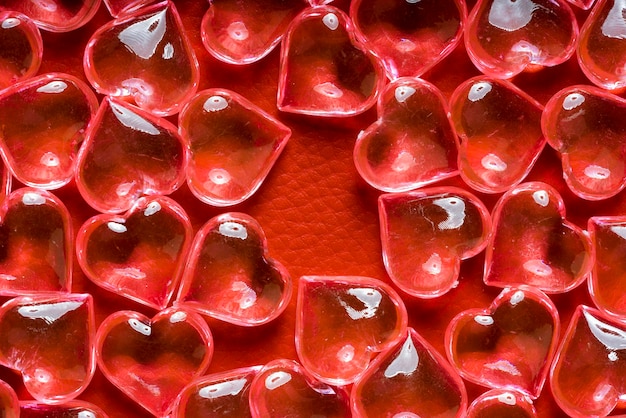 Corazones de vidrio transparente sobre un fondo de cuero rojo