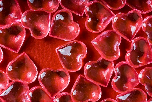 Corazones de vidrio transparente sobre un fondo de cuero rojo