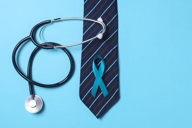 Corbata de estetoscopio y símbolo de cinta azul de la conciencia del cáncer de próstata aislado sobre fondo azul.