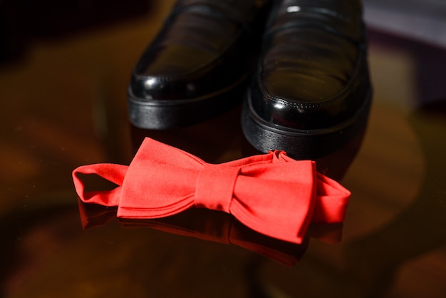 Corbata de mariposa roja y zapatos negros.