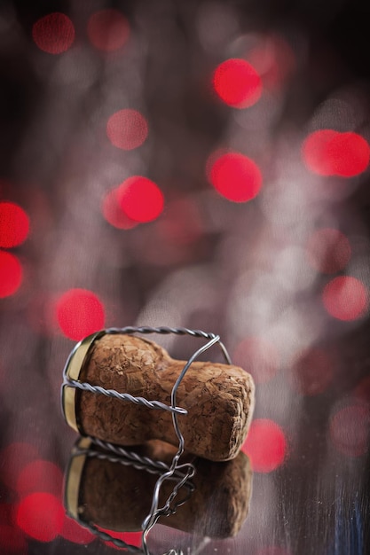 Corck de champanhe na superfície do espelho com luzes de bokeh vermelho