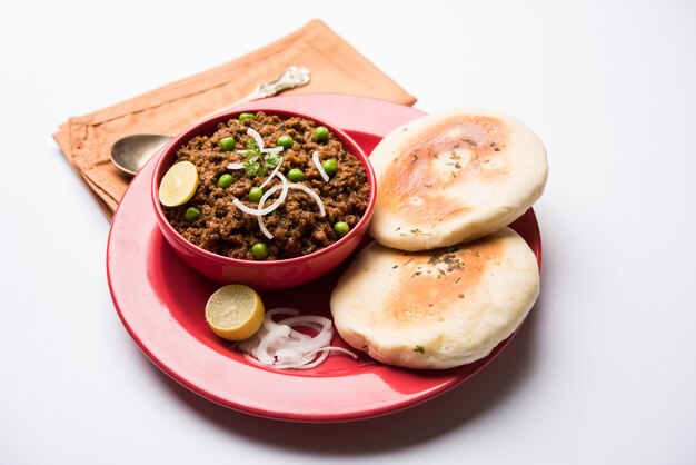 Cordero Kheema Pav O carne picada picante india servida con pan O kulcha, adornado con guisantes verdes. Fondo cambiante. Enfoque selectivo