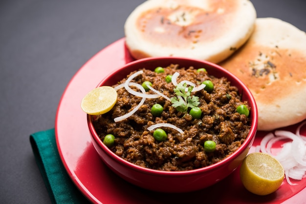 Cordero Kheema Pav O carne picada picante india servida con pan O kulcha, adornado con guisantes verdes. Fondo cambiante. Enfoque selectivo