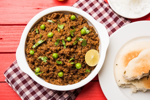 Cordero Kheema Pav O carne picada picante india servida con pan O kulcha, adornado con guisantes verdes. Fondo cambiante. Enfoque selectivo