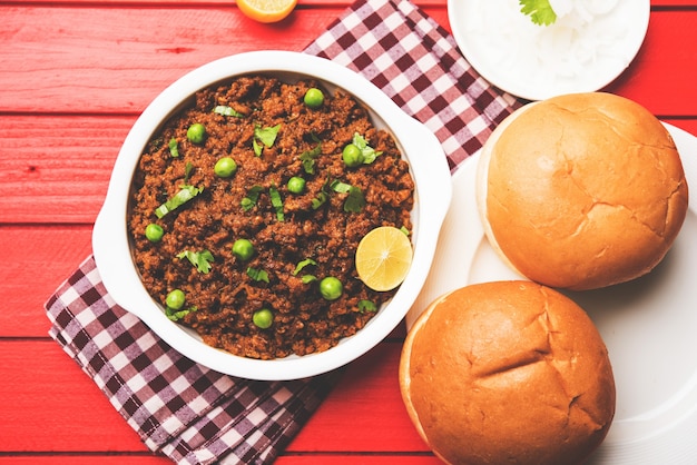 Cordero Kheema Pav O carne picada picante india servida con pan O kulcha, adornado con guisantes verdes. Fondo cambiante. Enfoque selectivo