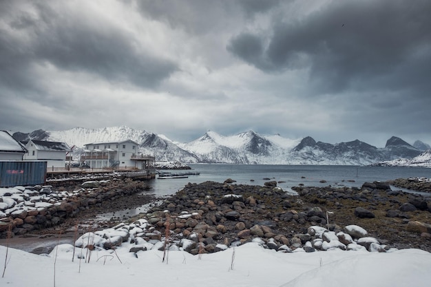 Cordilheira nevada com céu tempestuoso na vila de pescadores no litoral no inverno