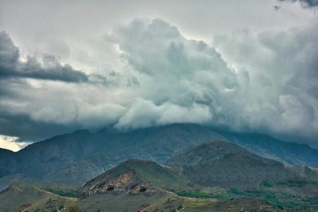 Foto una cordillera con un cielo nublado y montañas en el fondo